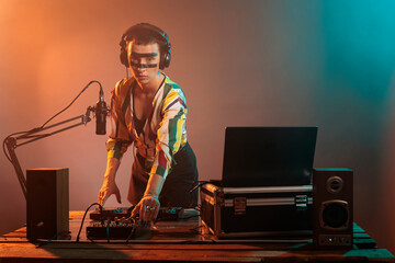 Young disc jockey mixing music on turntables, playing techno sounds with audio equipment in studio....