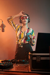 Tired female artist drinking coffee and yawning, feeling exhausted after nightclub party mixing...