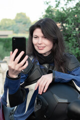 young beautiful brunette biker chatting with friends on a mobile phone