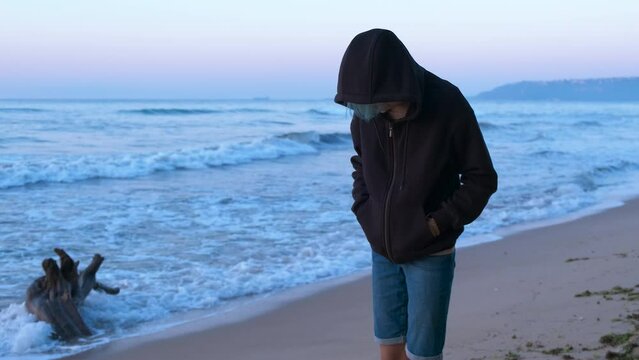 Girl stand in depression on sandy shore. A lonely teen feel depressed during her summer trip to the sea in the morning.