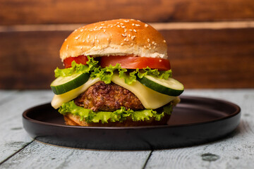 Burger in bun with beef meat and cheese, served on black plate