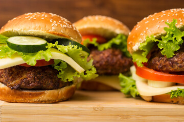 Delicious burgers with lettuce and cheese served on cutting board