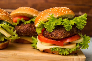 Delicious burgers with lettuce and cheese served on cutting board