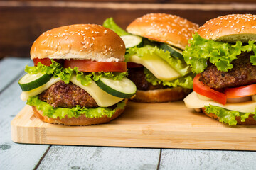 Delicious burgers with lettuce and cheese served on cutting board