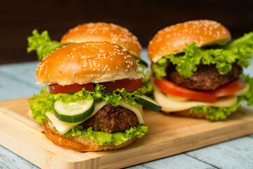 Delicious burgers with lettuce and cheese served on cutting board