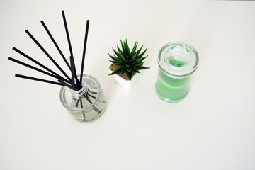 Incense sticks in a glass cubic vessel with essential oils. Interior decor. White background. Sansevier or aloe plant in a pot. Copy space. Wax candle in a stylish glass flask with a lid