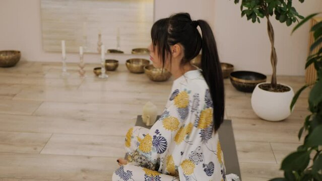 Beautiful woman doing yoga exercise against the background of Tibetan bowls and burning candles