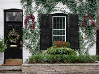 Fototapeta na wymiar Front of old brick house with Christmas wreath on front door and holly berry decorations