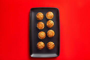 Chinese moon cakes on a black plate on a red background