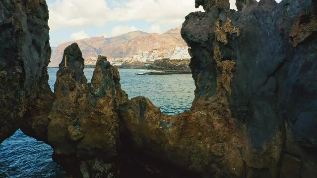 Natural ocean swimming pool of Devil. Aerial flight walk through dangerous rocks. Frozen black lava flows, volcanic bizzare stones, rocky beach. Tenerife Canary Islands. Charco El Diablo.