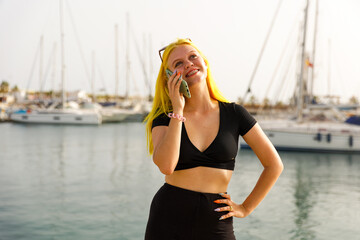 Beautiful woman in talking on the phone against the backdrop of the blue sea and yachts