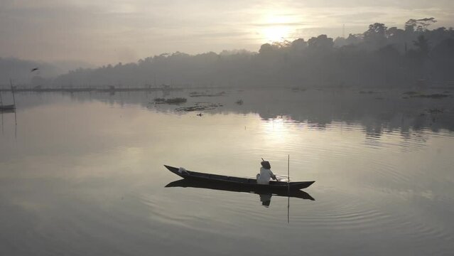 Semarang, Indonesia - Circa 2017: Traditional fisherman looking for freshwater fish at Rawa Pening lake during sunrise. Calm relax refreshing