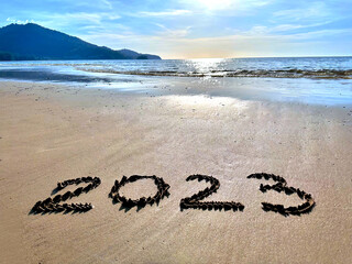 Letters, numbers 2023 written by hand on the sea beach on the sand. New year in summer vacation