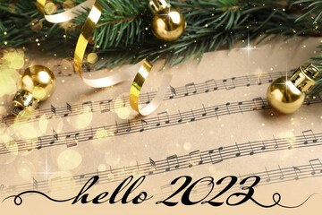Hello 2023. Fir branches and golden balls on Christmas music sheets, above view