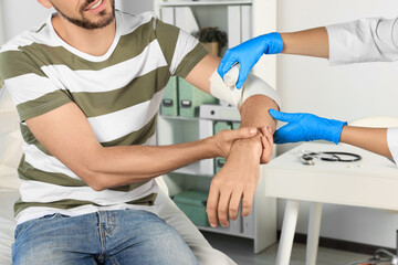 Fototapeta premium Doctor applying bandage onto patient's arm at hospital, closeup
