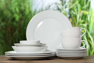 Set of clean dishware on wooden table against blurred background