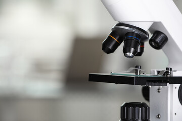 Modern medical microscope with glass slide on blurred background, closeup. Space for text