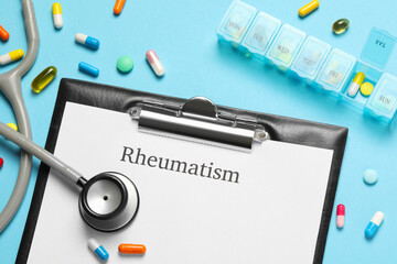 Clipboard with word Rheumatism, stethoscope and pills on light blue background, flat lay