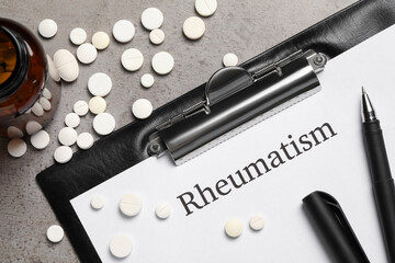 Clipboard with word Rheumatism and pills on light gray textured background, flat lay