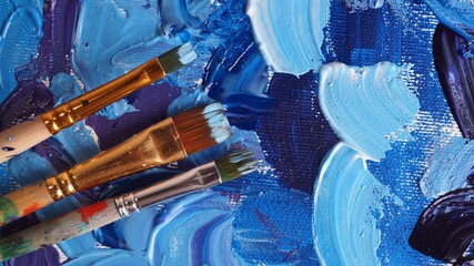 Brushes on canvas with mixed bright paints, flat lay