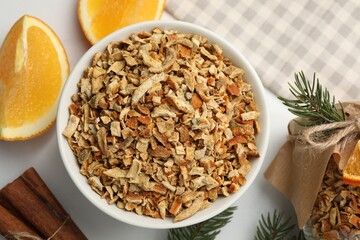 Bowl of dried orange zest seasoning, fresh fruit and cinnamon on white marble table, flat lay
