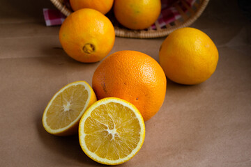 juicy ripe orange cut in half and oranges scattered from the basket on a light brown background