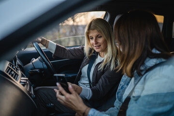 Fototapeta na wymiar two women drive in car travel use smartphone for gps map location