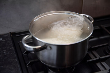 Woreczki z ryżem gotujące się w małym garnuszku na czarnej kuchence gazowej
