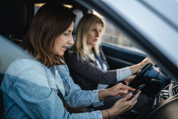 Naklejka na ściany i meble two women drive in car travel use smartphone for gps map location