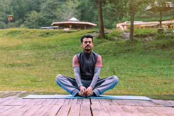Fototapeta na wymiar Mature man in lotus pose meditating in the forest.