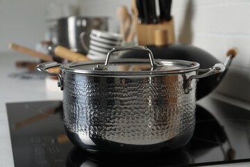 Metal pot on cooktop in kitchen, closeup. Cooking utensils