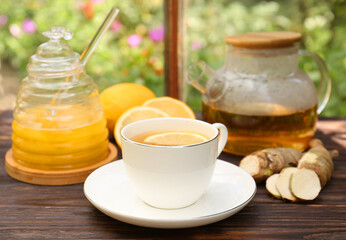 Cup of delicious tea with lemon and honey on wooden table