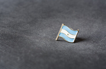 Argentina flag lapel metal pin on blue background. Copy space concept.