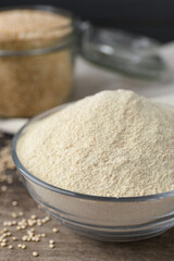 Glass bowl with quinoa flour and seeds on table, closeup