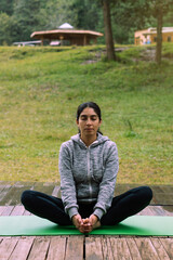 Fototapeta na wymiar Latina woman wearing sportswear, sitting in lotus position. Wellness.