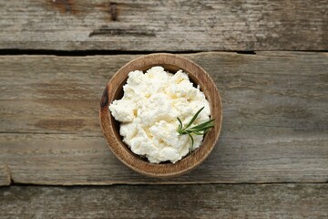 Fototapeta na wymiar Delicious tofu cream cheese with rosemary in bowl on wooden table, top view