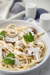 Delicious pasta with mushrooms on white tiled table, closeup