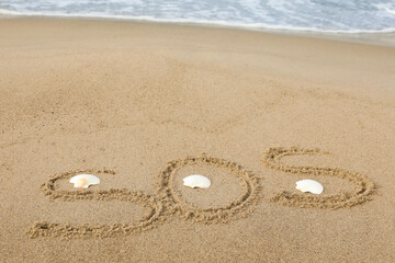 Message SOS drawn on sand near sea