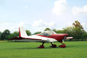 Fototapeta na wymiar Ultralight aircraft on green grass near trees