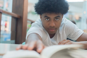Black teen boy in white shirt with black power hair reading umnlivro,various facial expressions and...