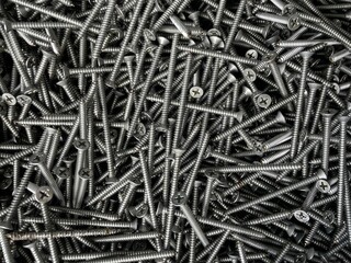 tapping screws made odd steel, metal screw, iron screw, chrome screw, screws as a background. Sharp screws on a black background.