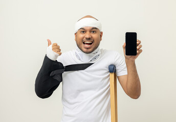 Happy young asian man broken arm holding smartphone. Asian man put on plaster bandage cast splint....