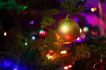 Christmas tree lights and gold ornament close up