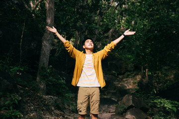 Teenager stands with raised arms in forest. Admiring nature, relaxing.