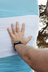 Left male hand touch a tree trunk dressed with the argentine flag