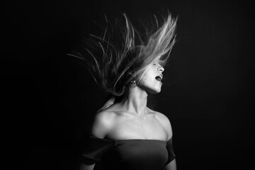 Fototapeta na wymiar Fashion and make-up concept. Studio portrait of beautiful woman with evening make-up and flying hair. Image contains motion blur. Model with sensual facial expression. Black and white image