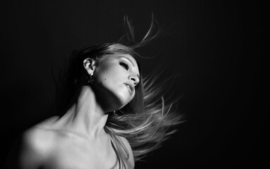 Fashion and make-up concept. Studio portrait of beautiful woman with evening make-up and flying hair. Image contains motion blur. Model with sensual facial expression. Black and white image