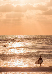 A picturesque seascape with a silhouette of a surfer in the foreground at sunset