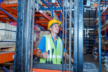 Portrait of a forklift driver wearing a hardhat and vest while moving stock around the floor of a carpet warehouse