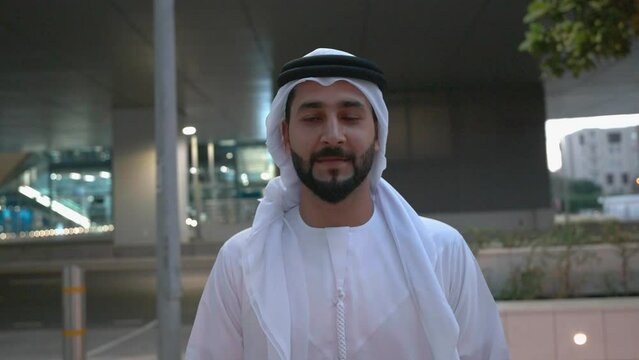 Walking Emirati UAE national wearing cultural Kandura and Ghutra men's wear common in Gulf and Middle East countries. Raw footage of  bearded man.